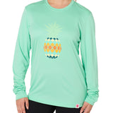 Front view of a female model wearing a mint green long sleeve performance shirt with a vibrantly colored retro pineapple graphic on the front.