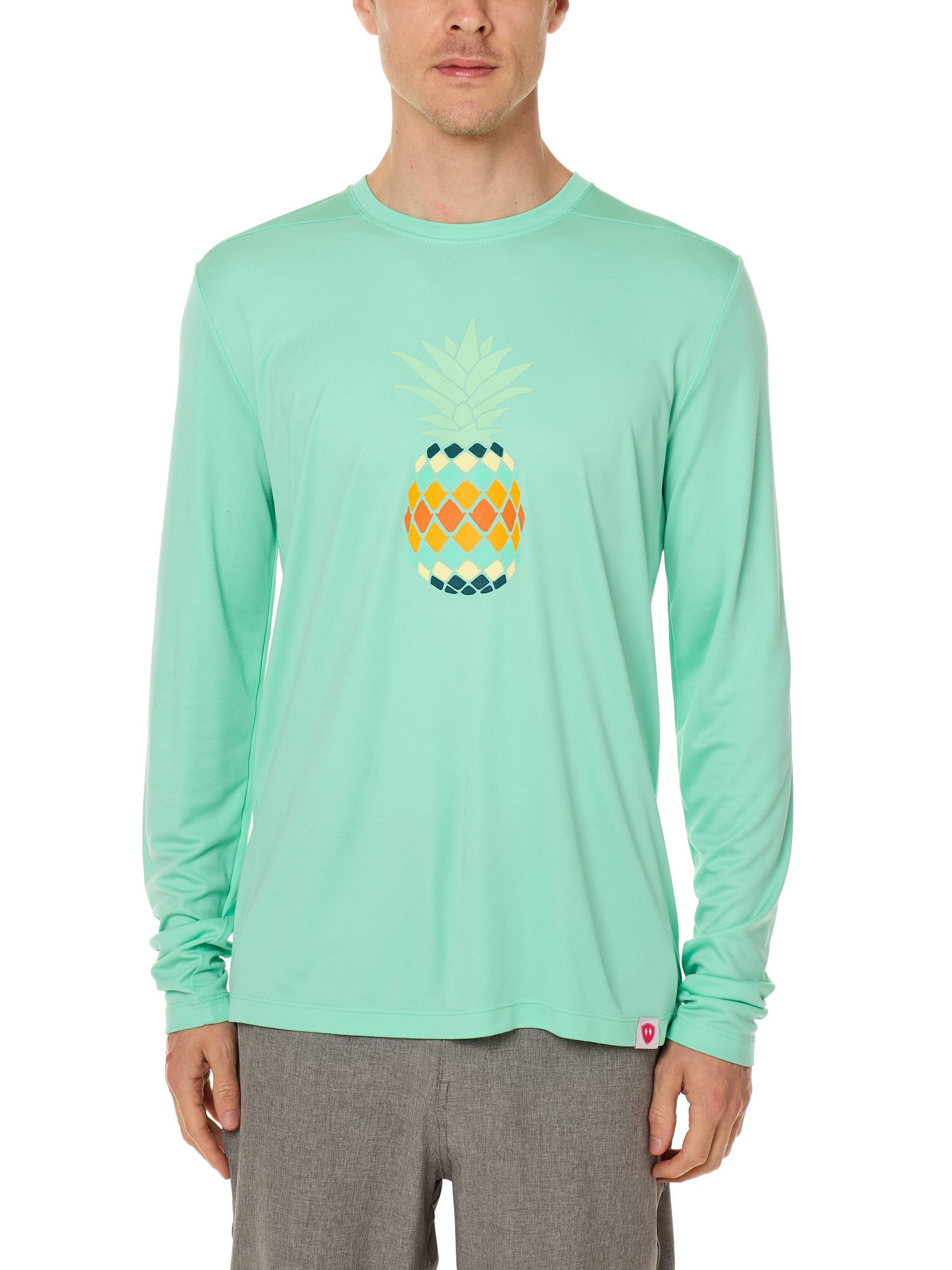 Front view of a male model wearing a mint green long sleeve performance shirt with a vibrantly colored retro pineapple graphic on the front.