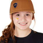 Front view of a youth wearing a caramel classic trucker hat with a navy blue embroidered double diamond shield on the bottom right panel