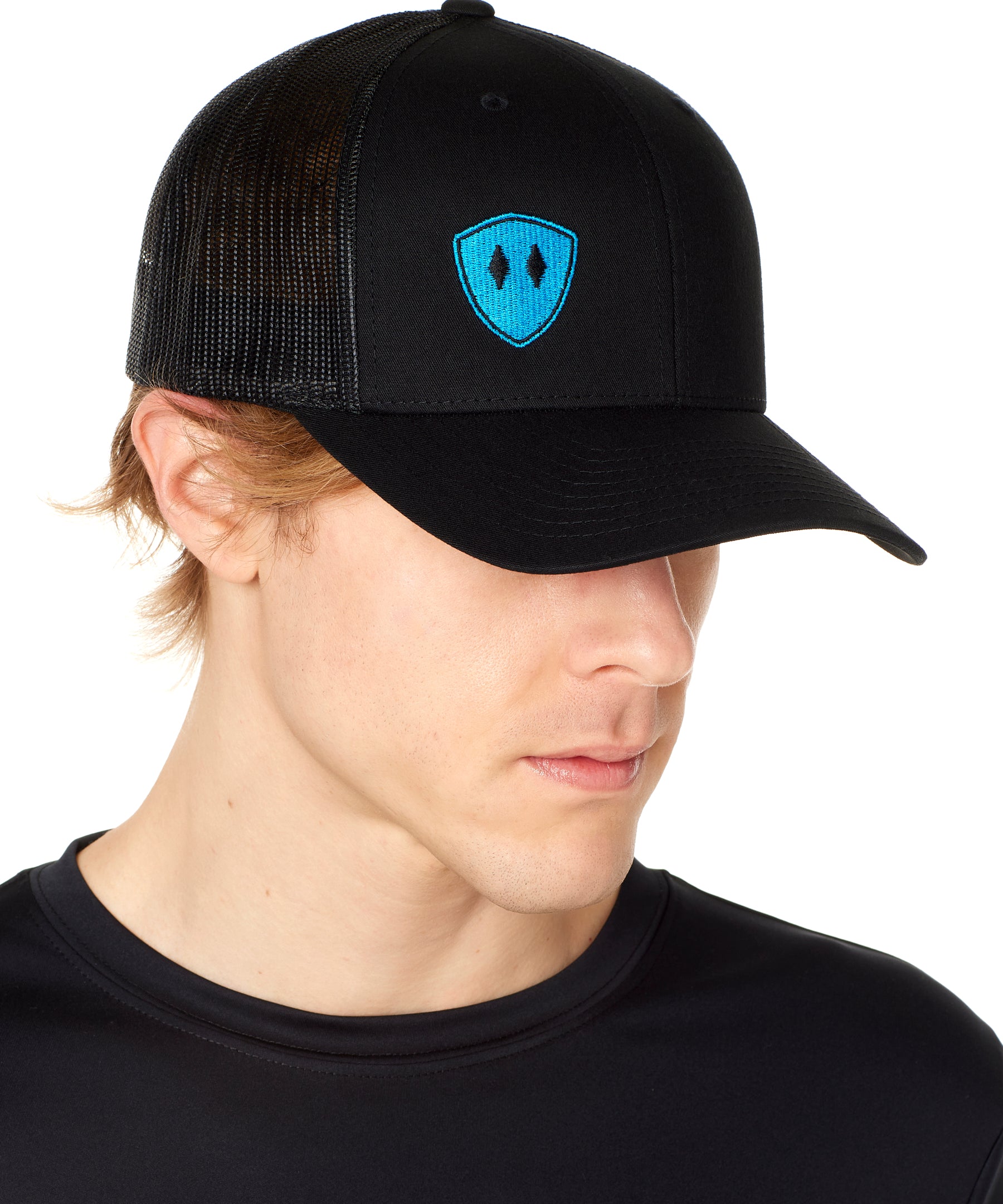 Front view of a male wearing a black classic trucker hat with a blue embroidered double diamond shield on the bottom right panel