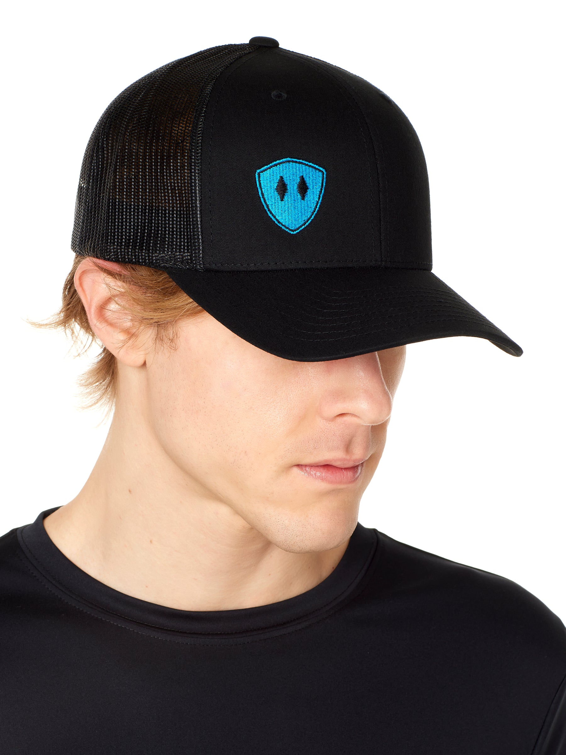 Front view of a male wearing a black classic trucker hat with a blue embroidered double diamond shield on the bottom right panel