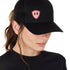 Front view of a female wearing a black classic trucker hat with a pink embroidered double diamond shield on the bottom right panel