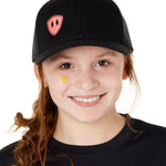 Front view of a youth wearing a black classic trucker hat with a pink embroidered double diamond shield on the bottom right panel