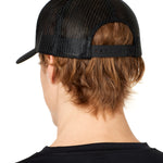 back view of a male model wearing a black classic trucker hat showing the mesh back panels and matching black snapback closure
