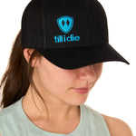 A woman wearing a black and blue snapback trucker hat with the Till I Die logo on the front.