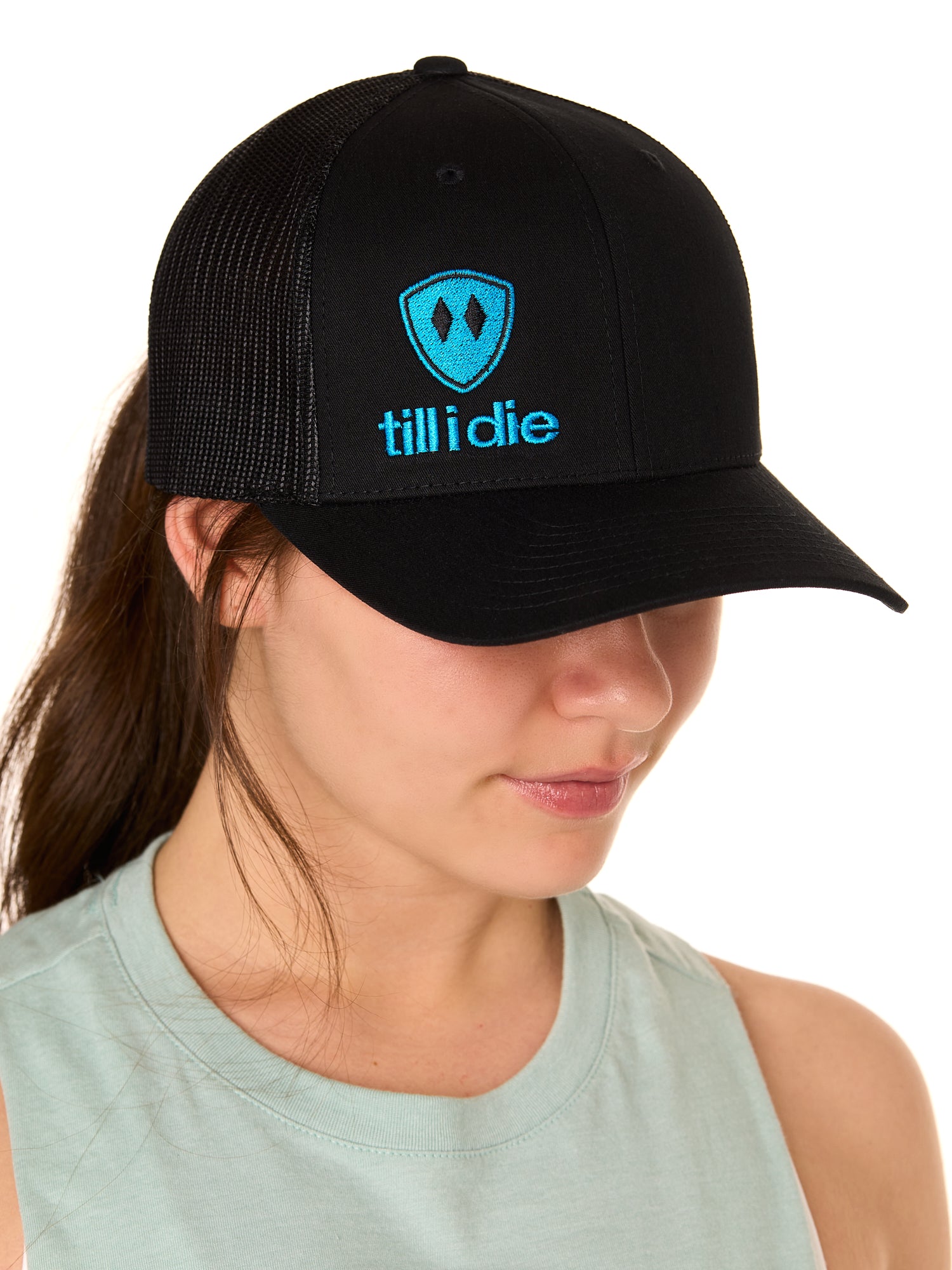 A woman wearing a black and blue snapback trucker hat with the Till I Die logo on the front.