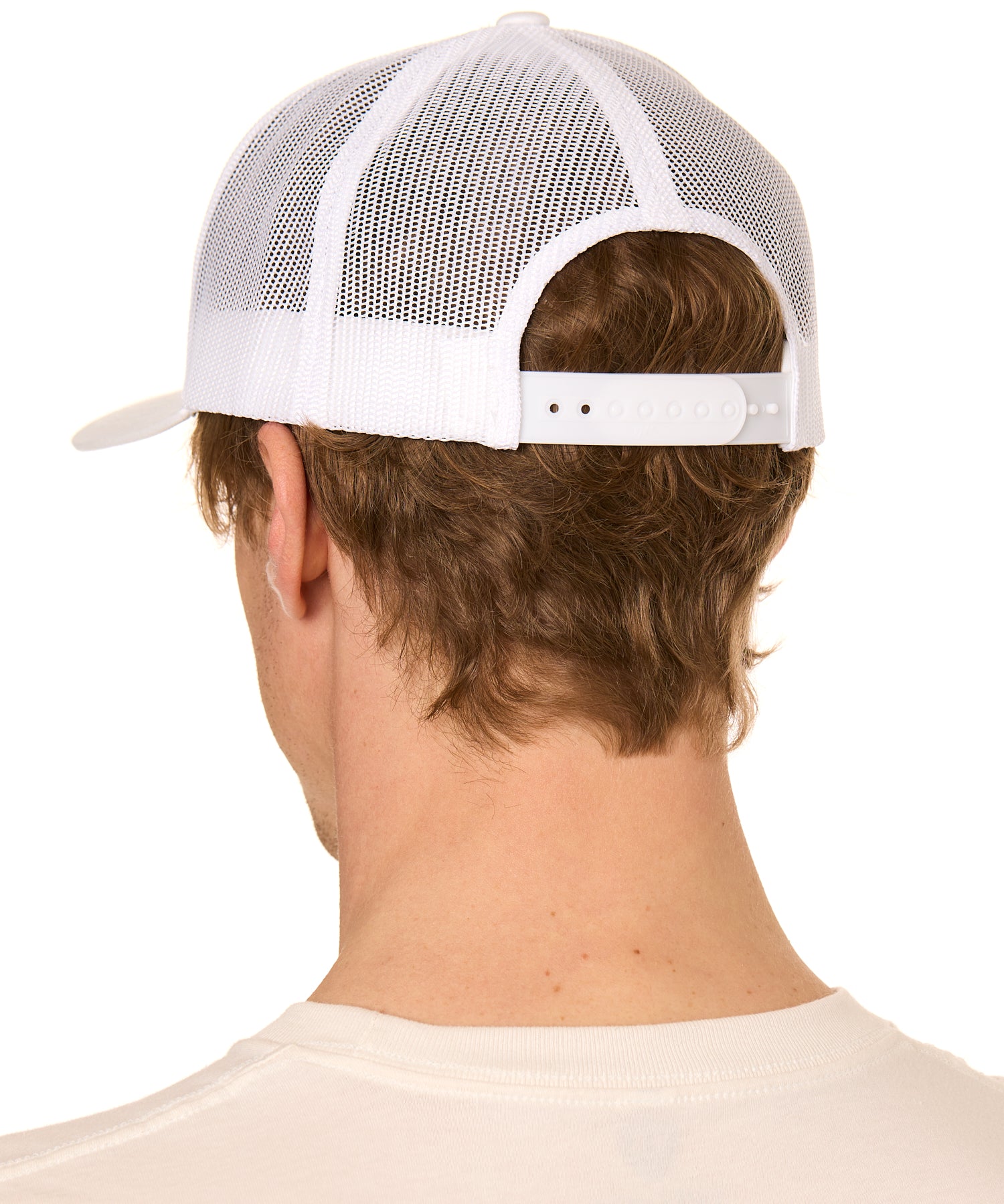 Back view of a male model wearing a classic white trucker hat featuring the mesh back panels and matching white snapback closure