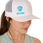 Front view of a female model wearing a white classic trucker hat, featuring a teal embroidered Till I Die logo on the lower right front panel.