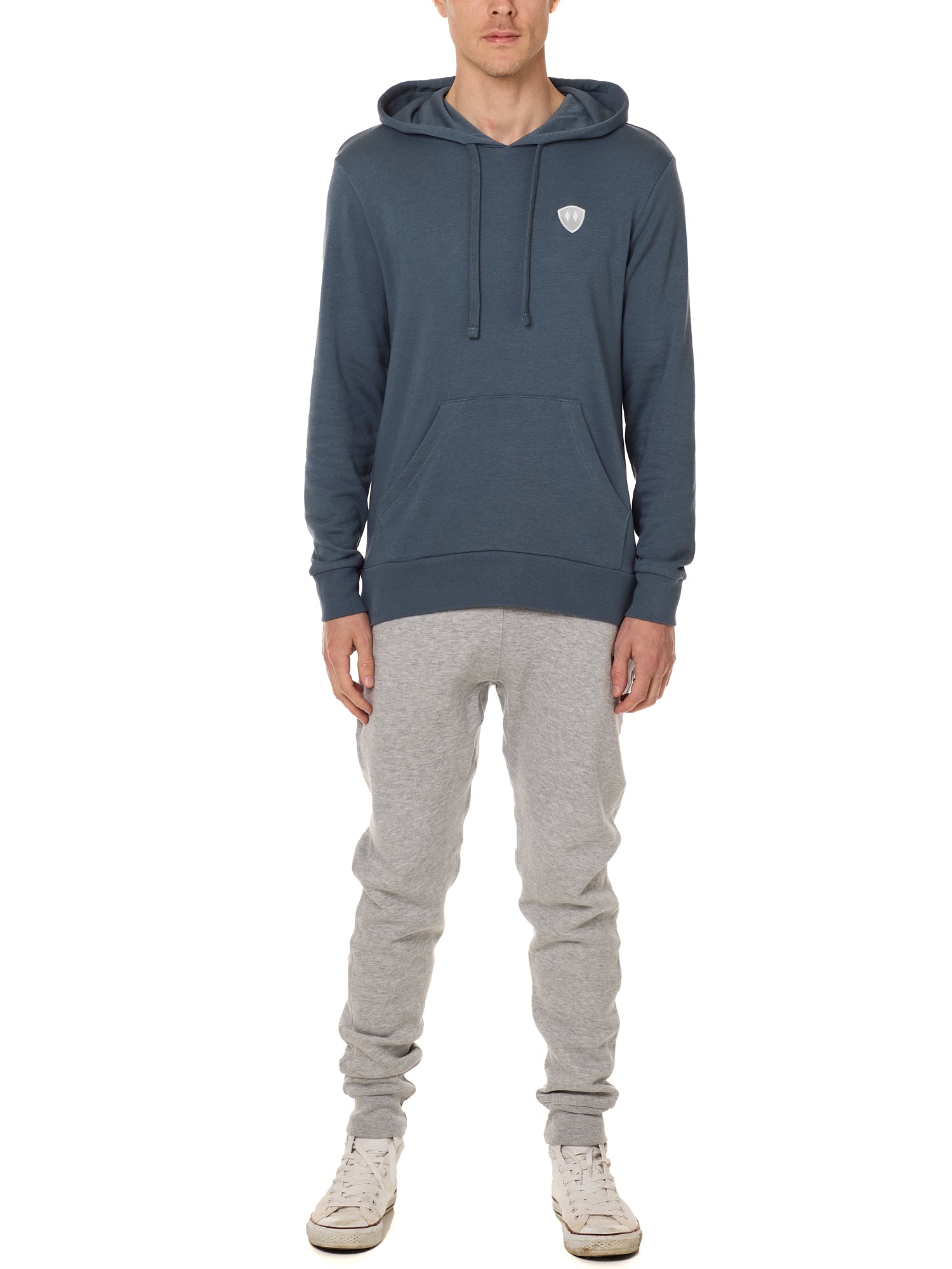 Front view of a male model wearing the Summer night hoodie in washed denim on a white background. The hoodie is embroider with a gray and white  double diamond shield over the wearers left chest. Paired with The Summer Nights mens joggers.