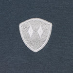 detail of a washed denim hoodie embroidered with a gray and white double diamond shield