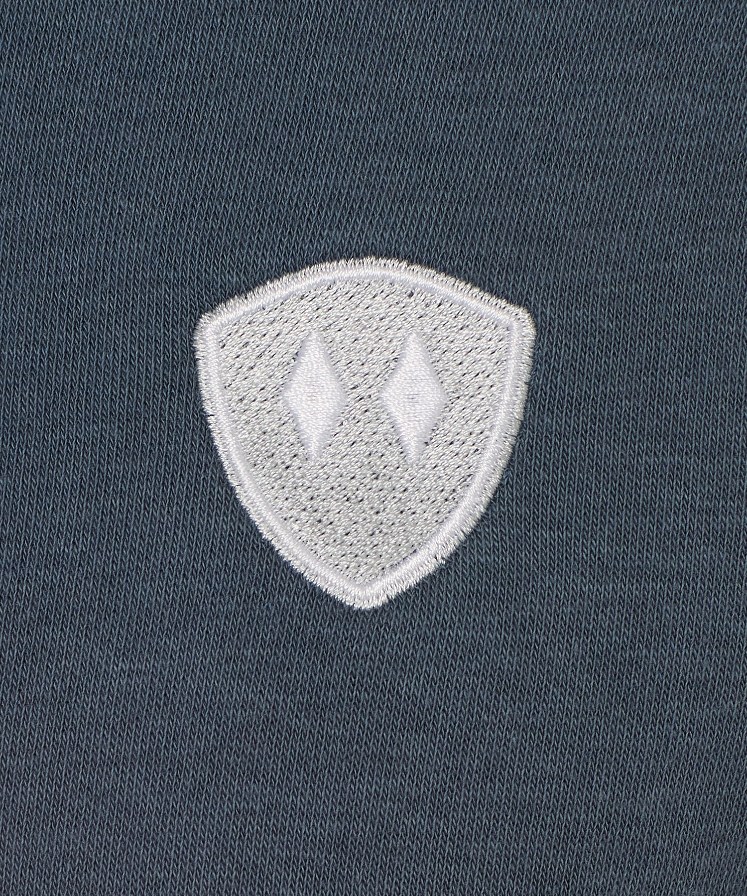 detail of a washed denim hoodie embroidered with a gray and white double diamond shield