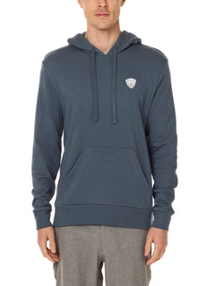 Front view of a male model wearing the Summer night hoodie in washed denim on a white background. The hoodie is embroider with a gray and white  double diamond shield over the wearers left chest.