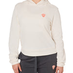 Front view of a female model wearing the vintage white Classic Hoodie on a white background, featuring a coral embroidered Double Diamond Shield on the wearer’s left chest.
