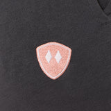 detail of a charcoal jogger embroidered with a coral and white double diamond shield