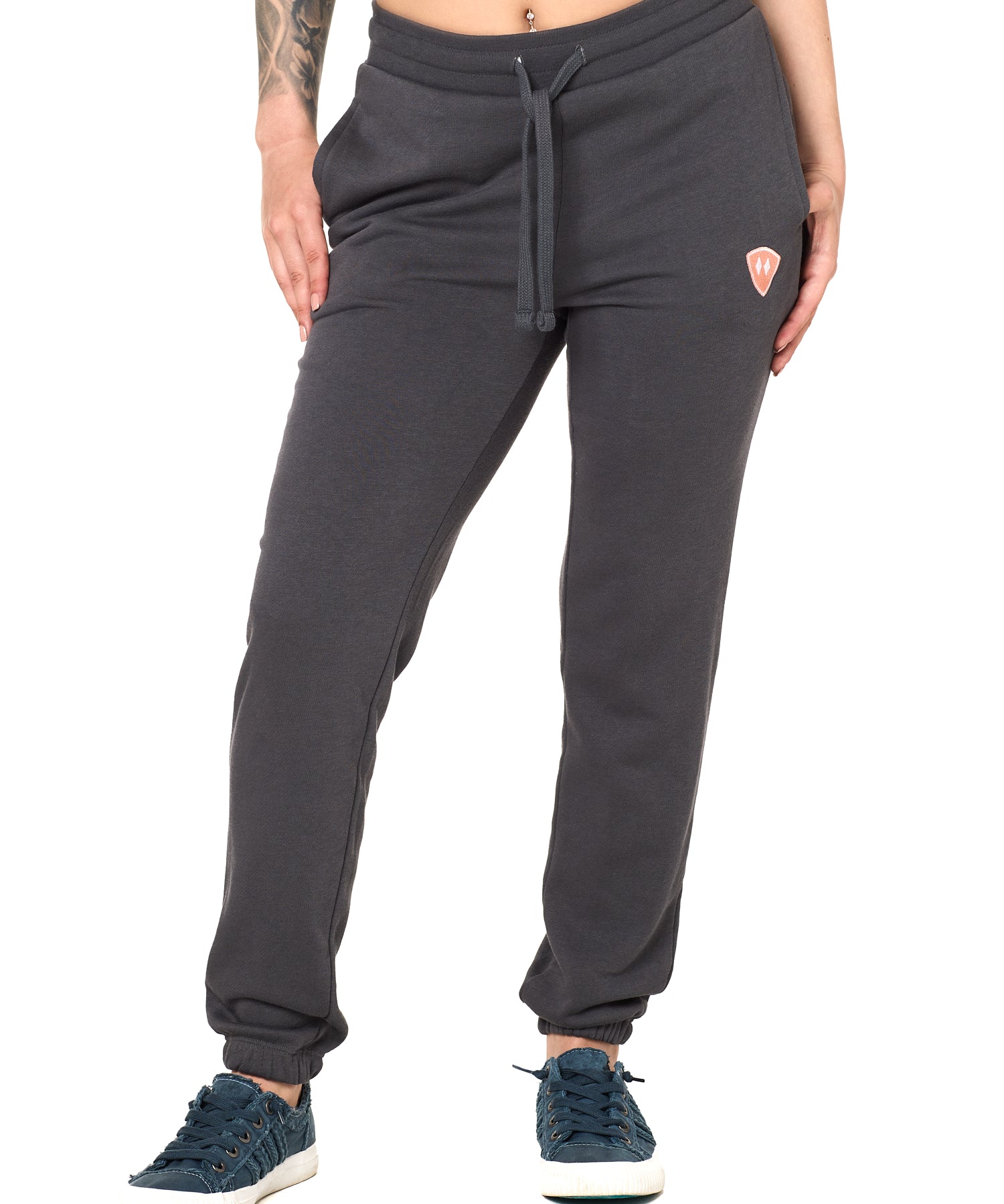 Front view of a female model wearing the women's summer night charcoal joggers. The joggers have a dyed to match drawstring and coral and white embroidered double diamond logo near the left pocket.