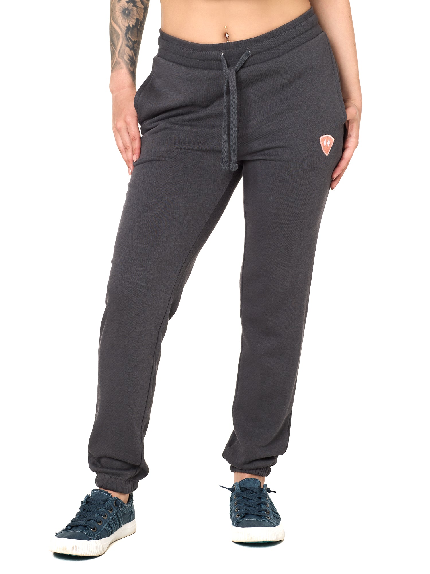 Front view of a female model wearing the women's summer night charcoal joggers. The joggers have a dyed to match drawstring and coral and white embroidered double diamond logo near the left pocket.