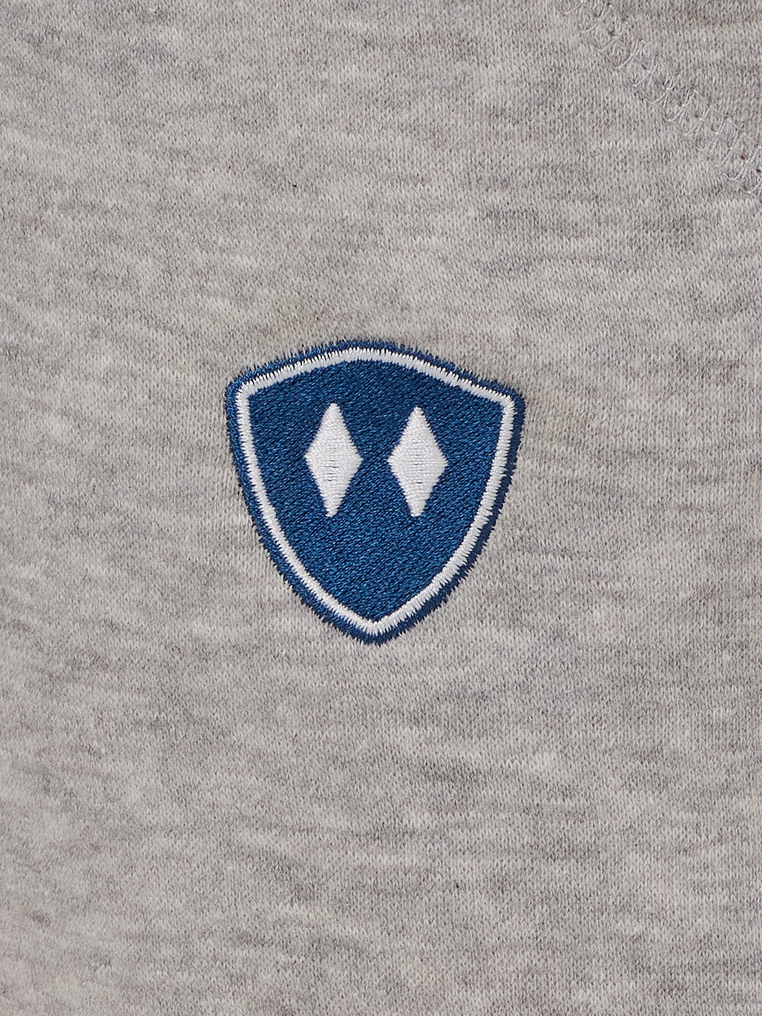 detail of a heather gray jogger embroidered with a blue and white double diamond shield