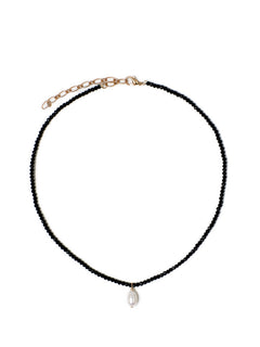 Top view of the Beachcomber’s Jewel necklace, featuring faceted, high-shine black glass beads. Anchored in the center with a freshwater pearl and fastened with a gold lobster clasp.