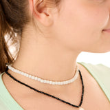 close up view of a female model wearing the black beachcombers necklace layered with the gray echoes of Atlantis necklace