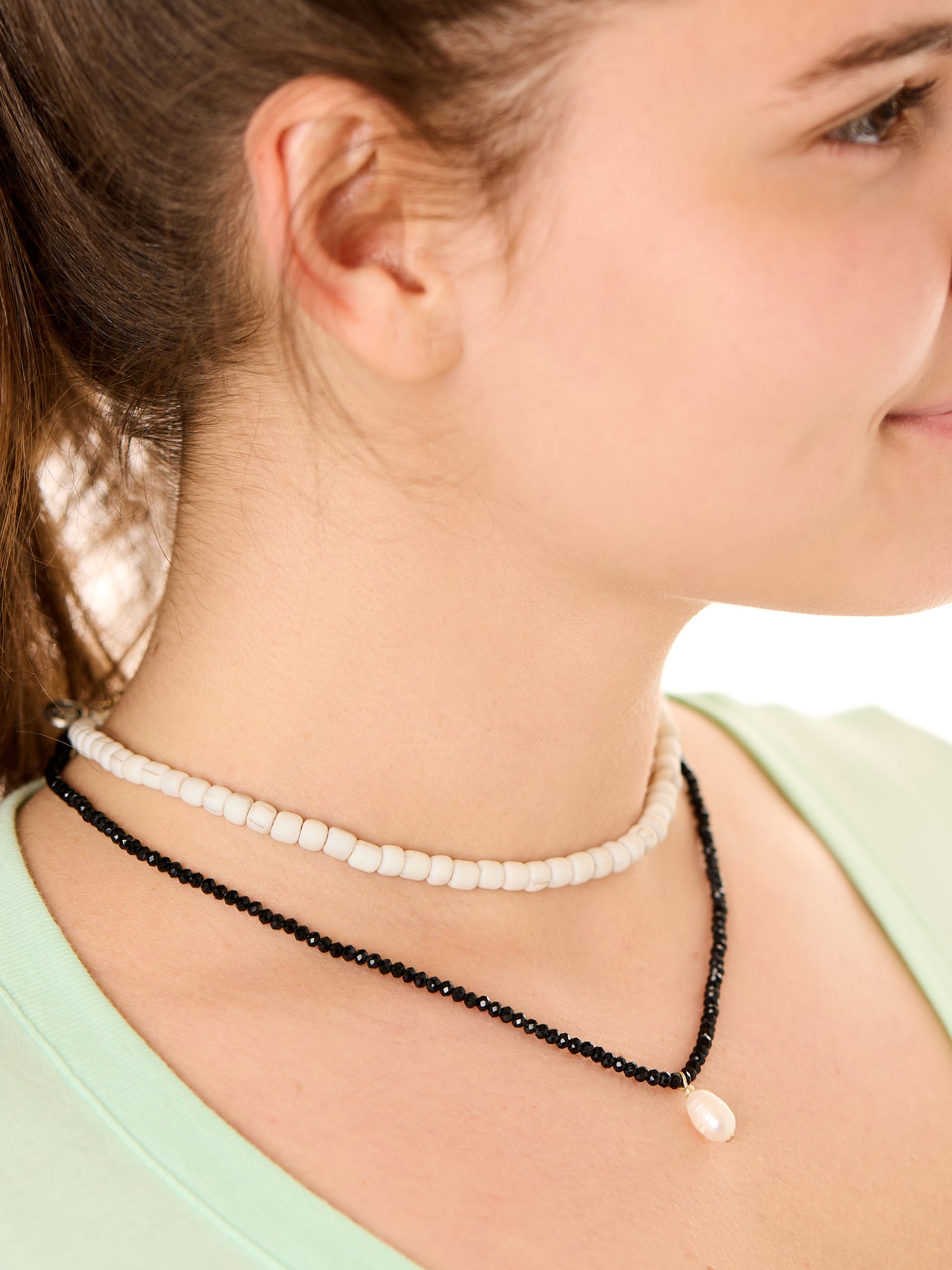 close up view of a female model wearing the black beachcombers necklace layered with the gray echoes of Atlantis necklace