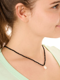 close up view of a female model wearing the black beachcombers necklace