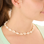 Close-up view of a female model wearing the cream Outer Banks Cowrie necklace 