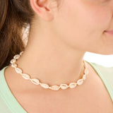 Close-up view of a female model wearing the cream Outer Banks Cowrie necklace 