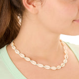 Close-up view of a female model wearing the turquoise Outer Banks Cowrie necklace 