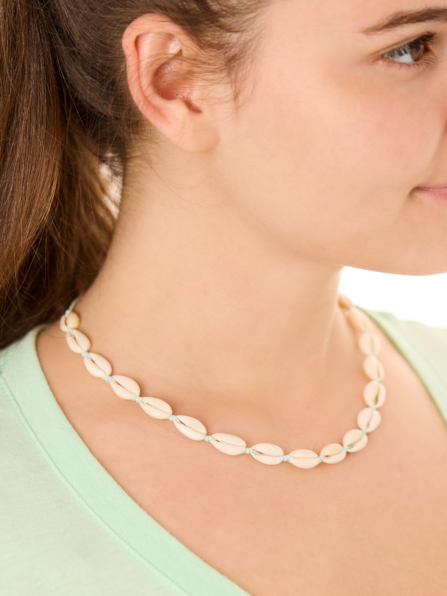Close-up view of a female model wearing the turquoise Outer Banks Cowrie necklace 
