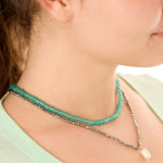Close-up view of a female model wearing the green Echoes of Atlantis necklace layered with the gray Beachcomber’s Jewel necklace.