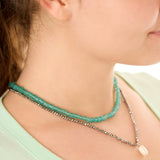 Close-up view of a female model wearing the green Echoes of Atlantis necklace layered with the gray Beachcomber’s Jewel necklace.