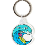 Front view of the Surfer Skeleton clear acrylic keychain, featuring a multicolored circular graphic of a skeleton surfing a wave, with “Till I Die” text at the top. The transparent acrylic enhances the vividness of the design.