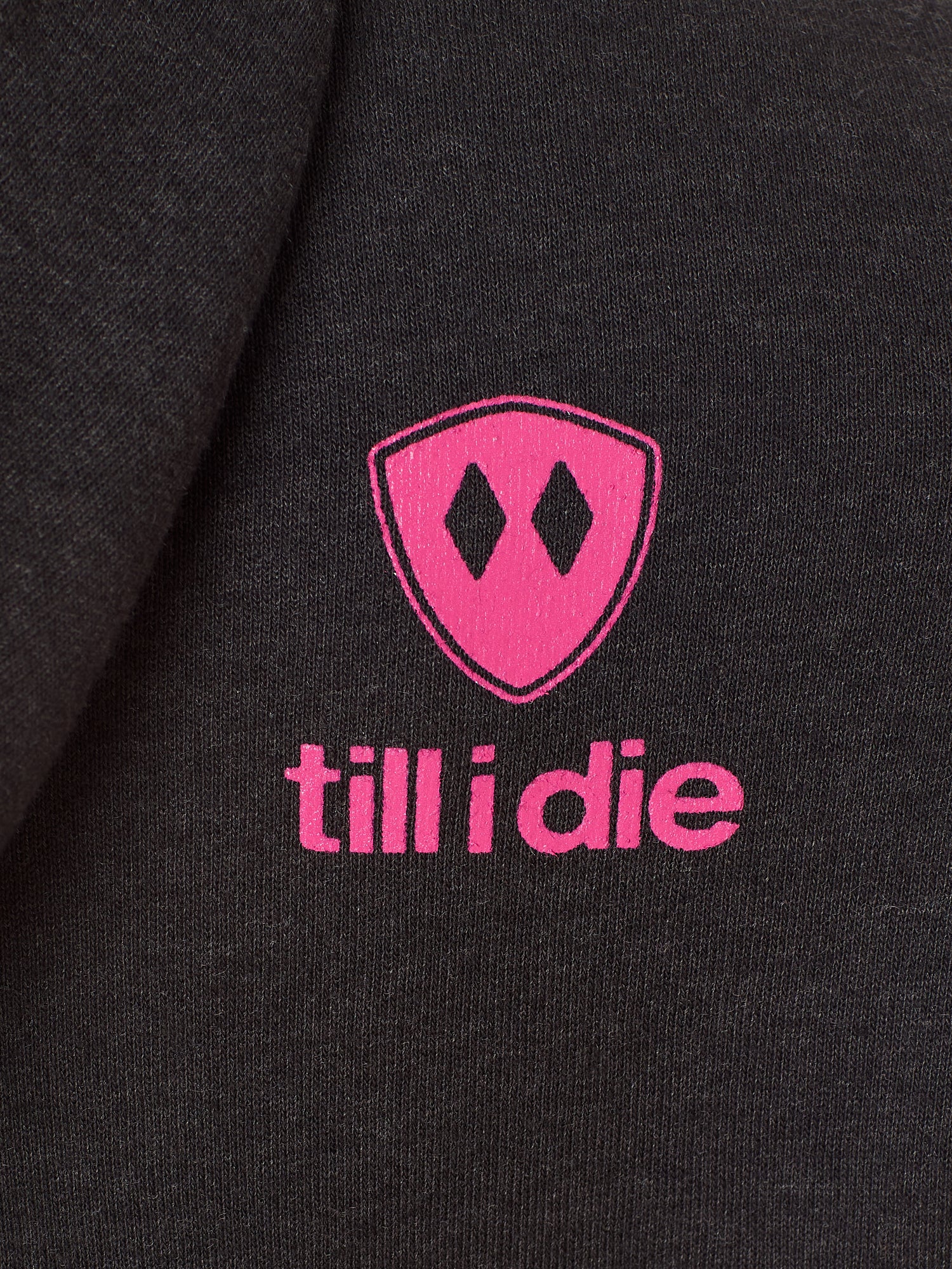 Detail of the hot pink till i die logo on a heather black hoodie