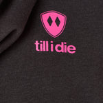 Detail of the hot pink till i die logo on a heather black hoodie