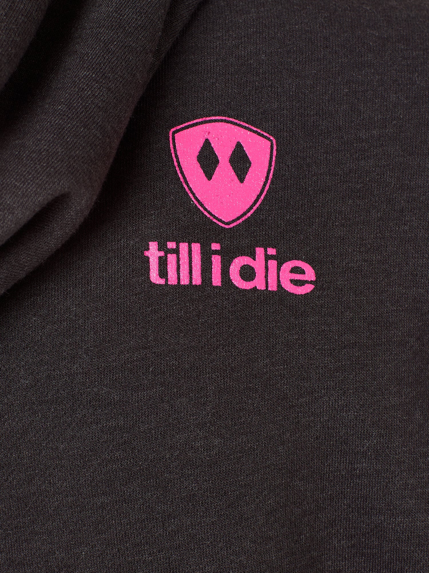 Detail of the hot pink till i die logo on a heather black hoodie
