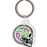 Front view of the Gear Head clear acrylic keychain, featuring a multicolored circular graphic of a skeleton with gears accenting the skull, with “Till I Die” text at the top. The transparent acrylic enhances the vividness of the design.