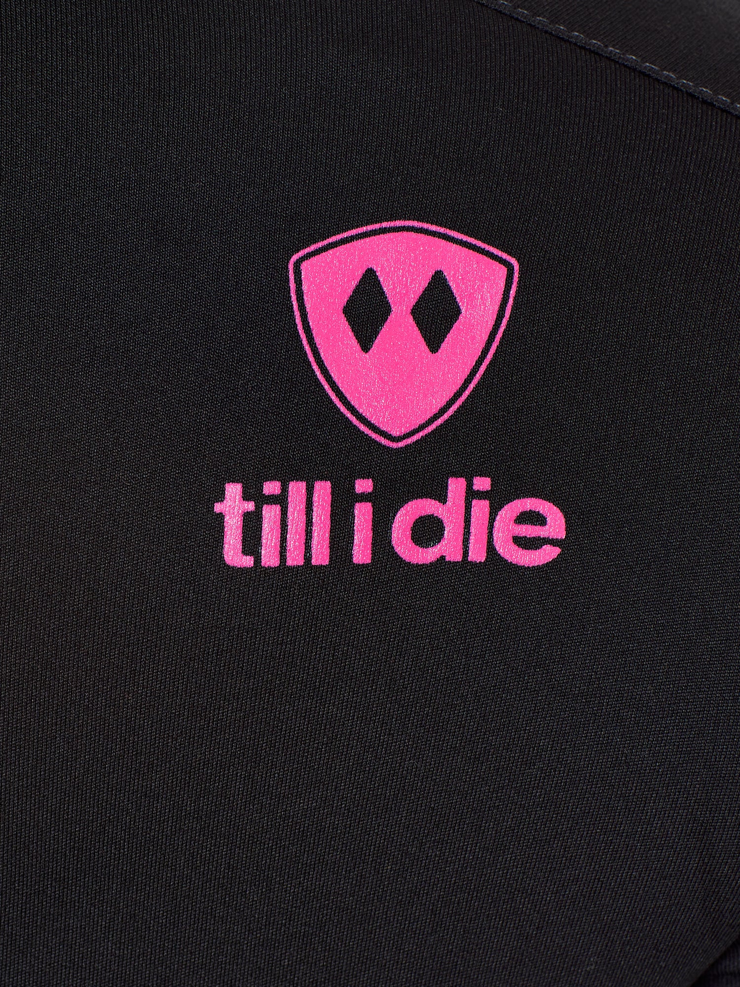 Detail of the hot pink till i die logo on a black performance long sleeve shirt