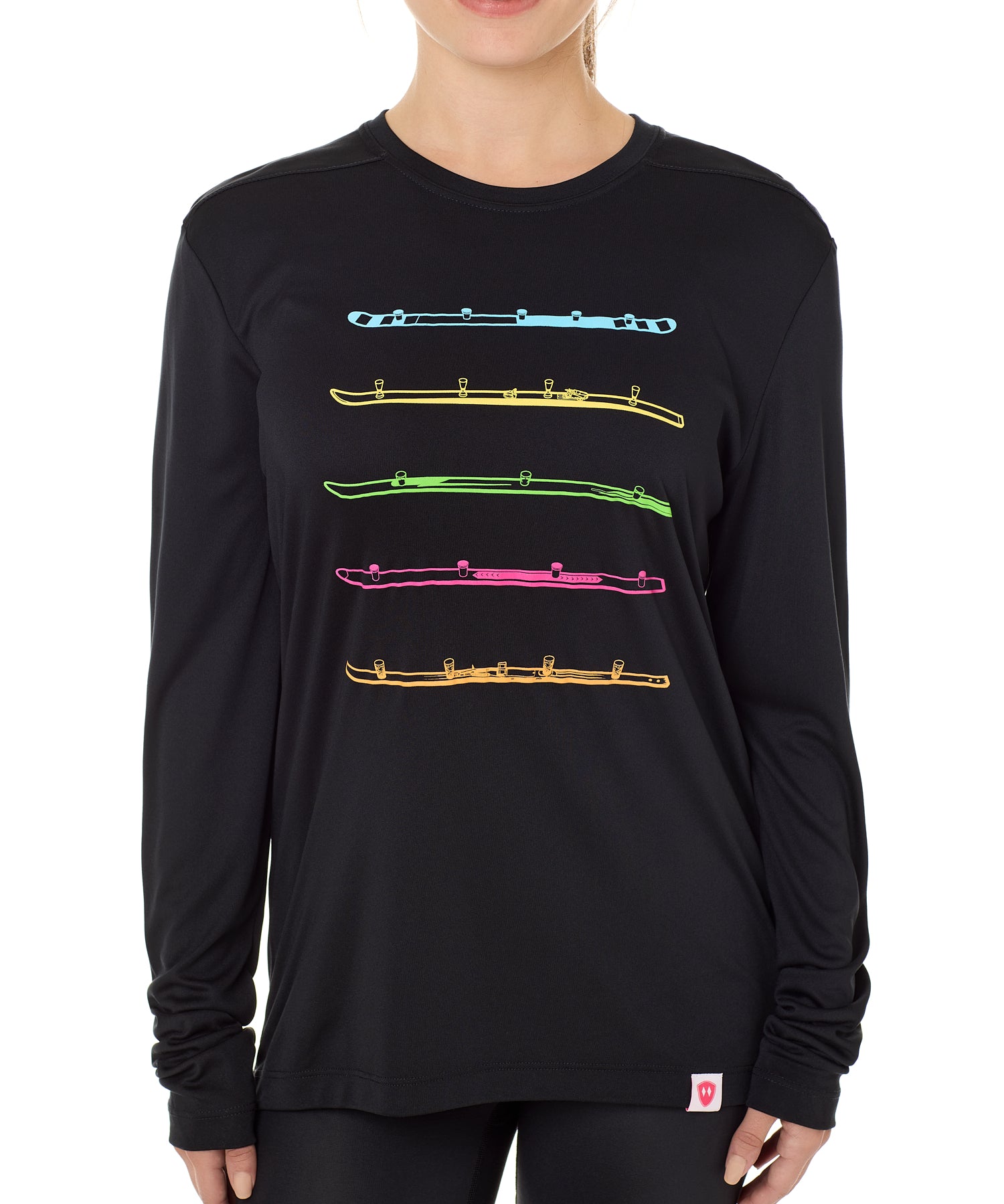 Front view of a female model wearing the black Shot Ski performance long sleeve shirt on a white background. Graphic features five multicolored shot skis illustrated in a line art style across the front.