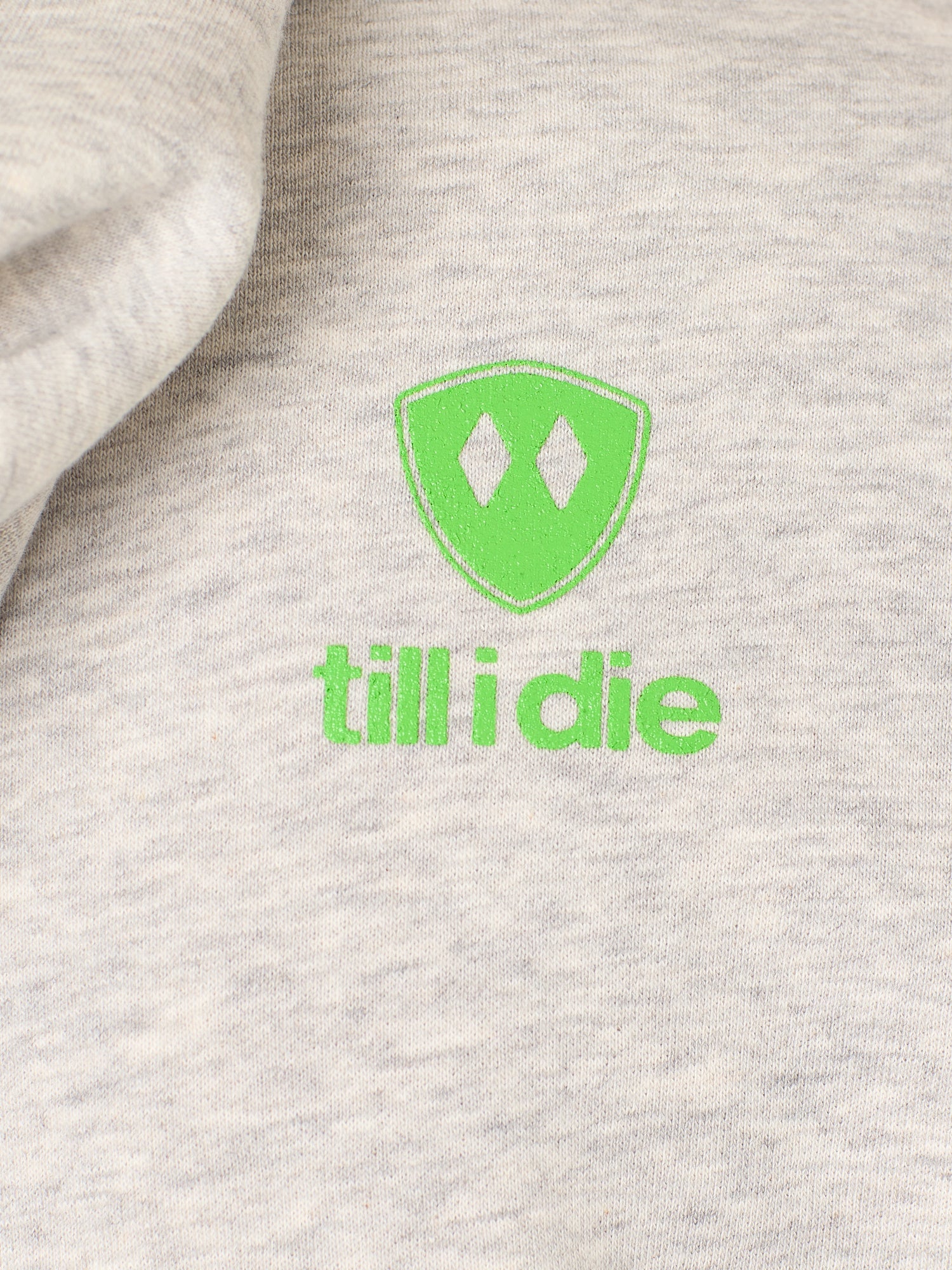 Detail of the Lime Green till i die logo on a heather oatmeal hoodie