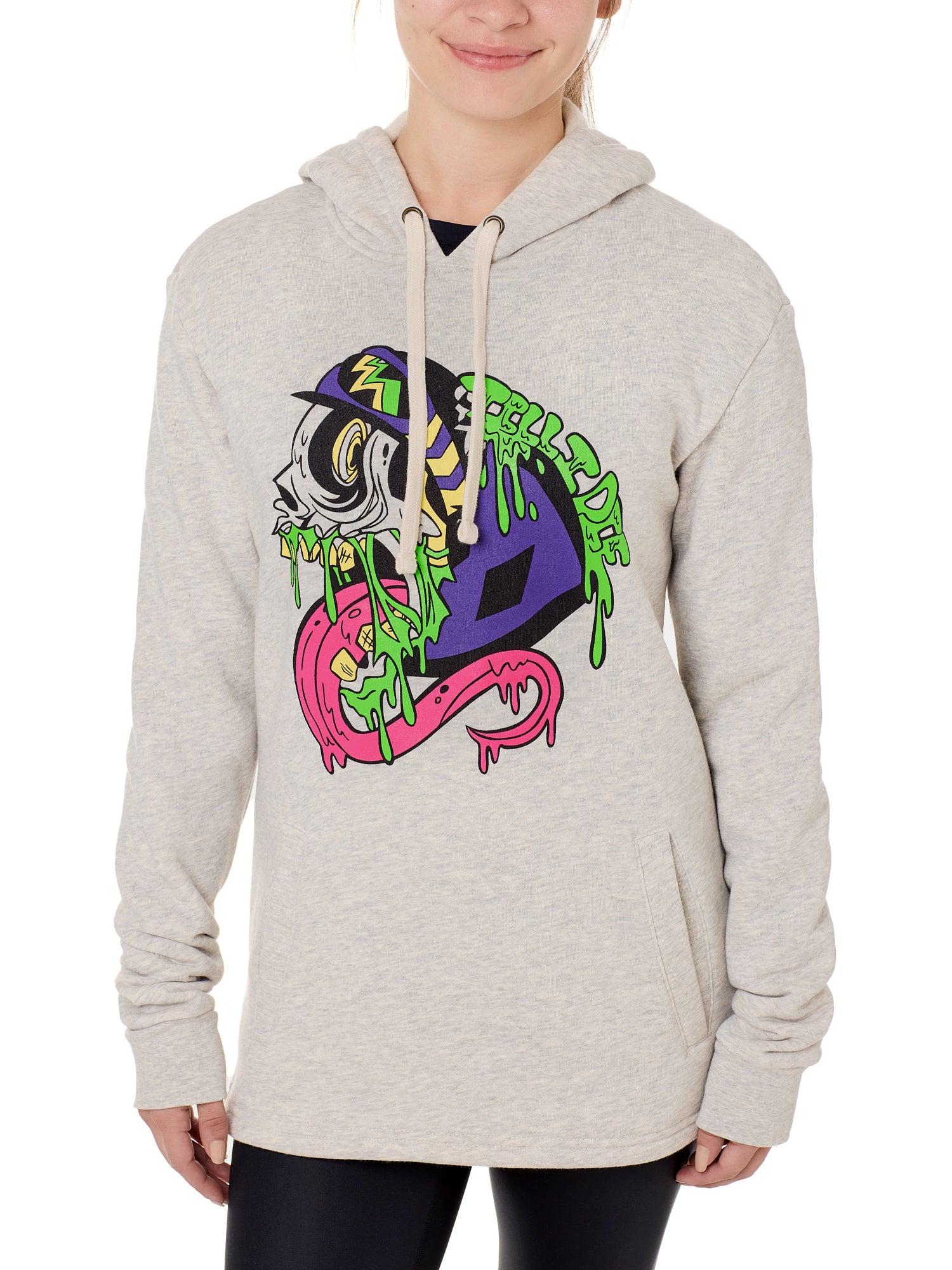 Front view of a female model wearing the Steezy Stan Hoodie in Heather Oatmeal on a white background. The graphic features a multicolored zombie skier with a long tongue, dripping slime, the Double Diamond Shield bursting from its skull, and oozing "Till I Die" text in a sludge-like style.
