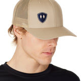 MAN WEARING A TAN TRUCKER HAT WITH NAVY DOUBLE DIAMOND SHIELD LOGO
