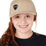 YOUTH WEARING A TAN TRUCKER HAT WITH NAVY DOUBLE DIAMOND SHIELD LOGO