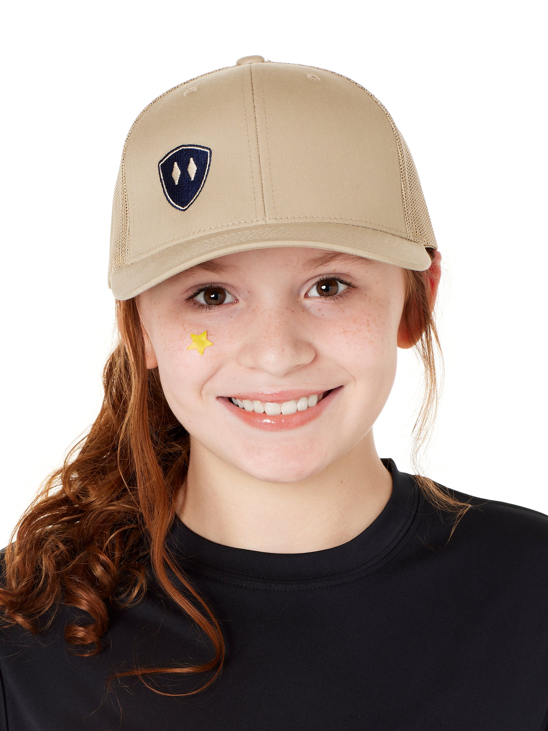 YOUTH WEARING A TAN TRUCKER HAT WITH NAVY DOUBLE DIAMOND SHIELD LOGO