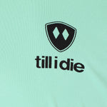 Detail of the black till i die logo on a mint green performance long sleeve shirt