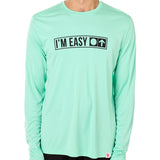 Front view of a male model wearing the "I'm Easy" Mint Green Long Sleeve Performance Shirt. The graphic features trail sign-inspired "I'm Easy" text with a circle symbol indicating beginner terrain.