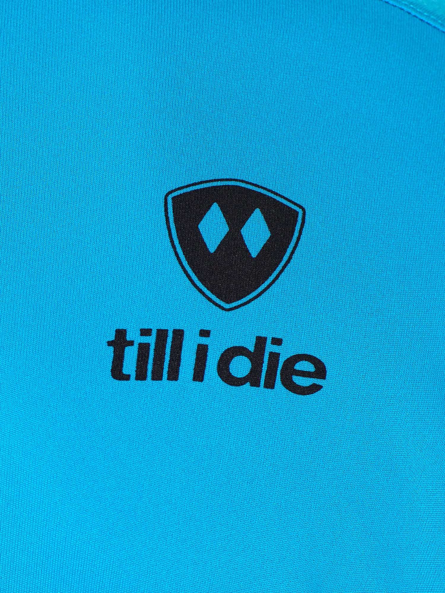 Detail of the black till i die logo on a Sapphire blue performance long sleeve shirt