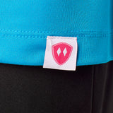 Close-up detail of a pink Double Diamond Shield woven hem label on a sapphire blue performance long sleeve shirt.