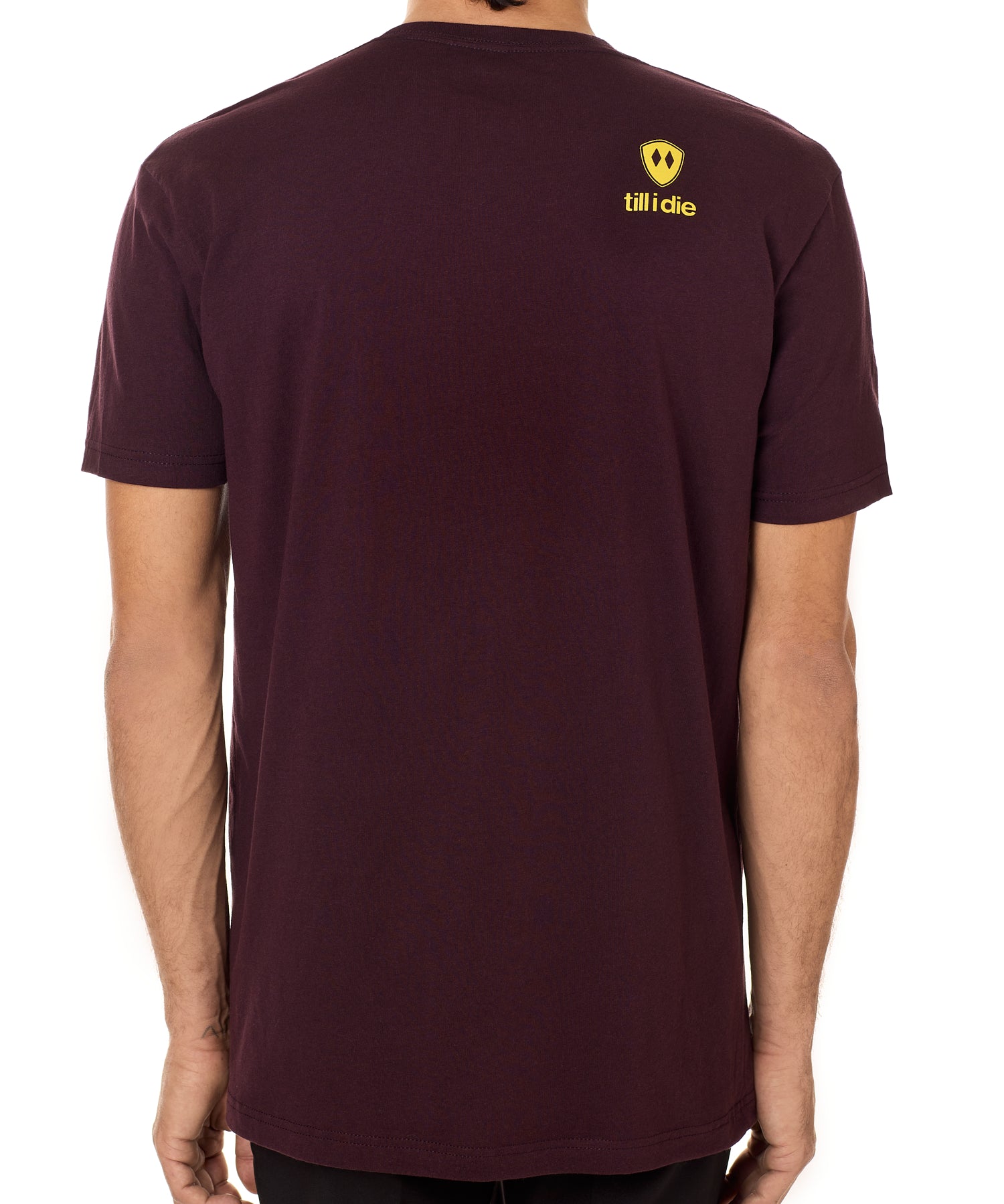 Back view of a male model wearing an oxblood tee shirt accented with a yellow till i die logo on wearers top right shoulder.