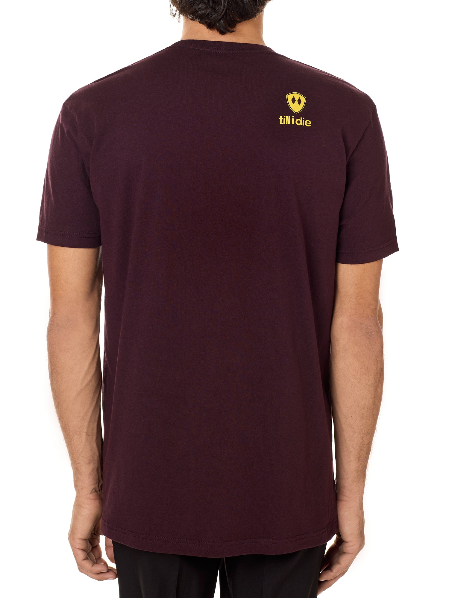 Back view of a male model wearing an oxblood tee shirt accented with a yellow till i die logo on wearers top right shoulder.