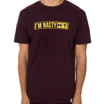 Front view of a male model wearing the "I'm Nasty" Oxblood Tee Shirt. The graphic features trail sign-inspired "I'm Nasty" text with a double diamond symbol indicating expert terrain.